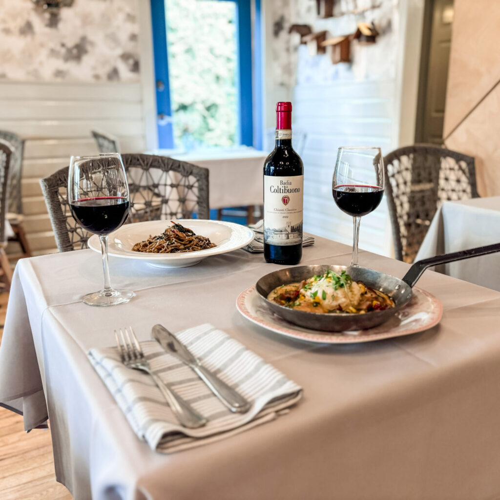Wine Down Wednesday at flora, a bottle of wine with two glasses poured and two entrées